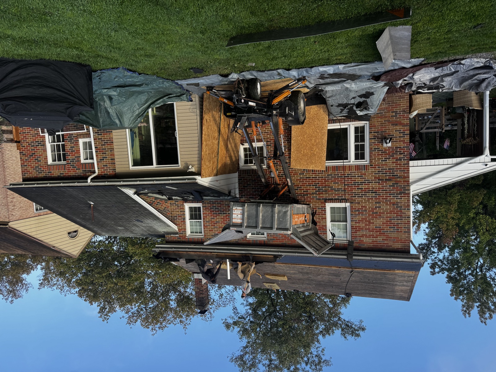 Roof tear-off in progress on a two-story brick home